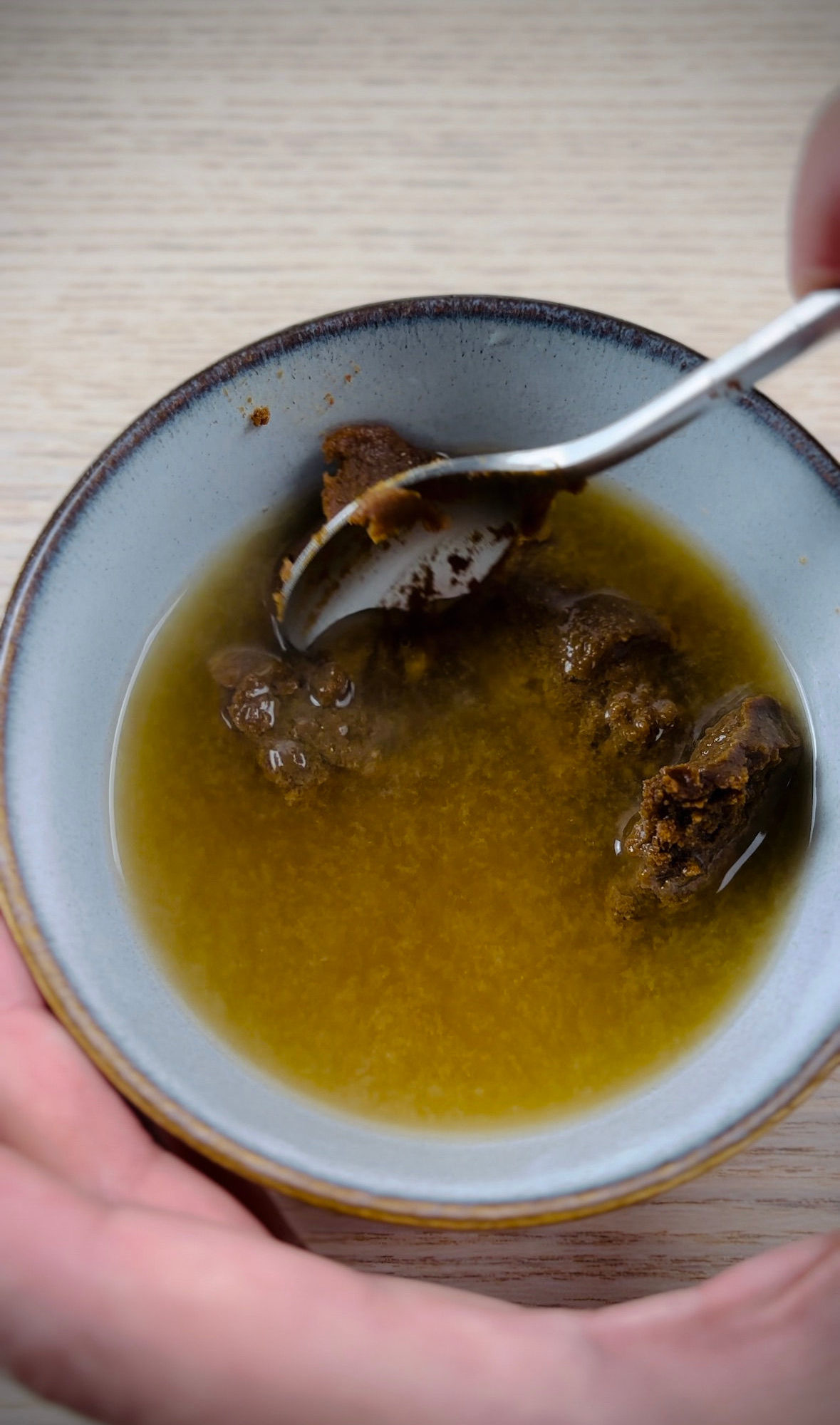 A teaspoon smoothing miso paste in to water in a small bowl.