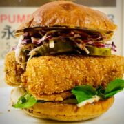 Vegan tofu katsu burger in a bun with toppings on a plate