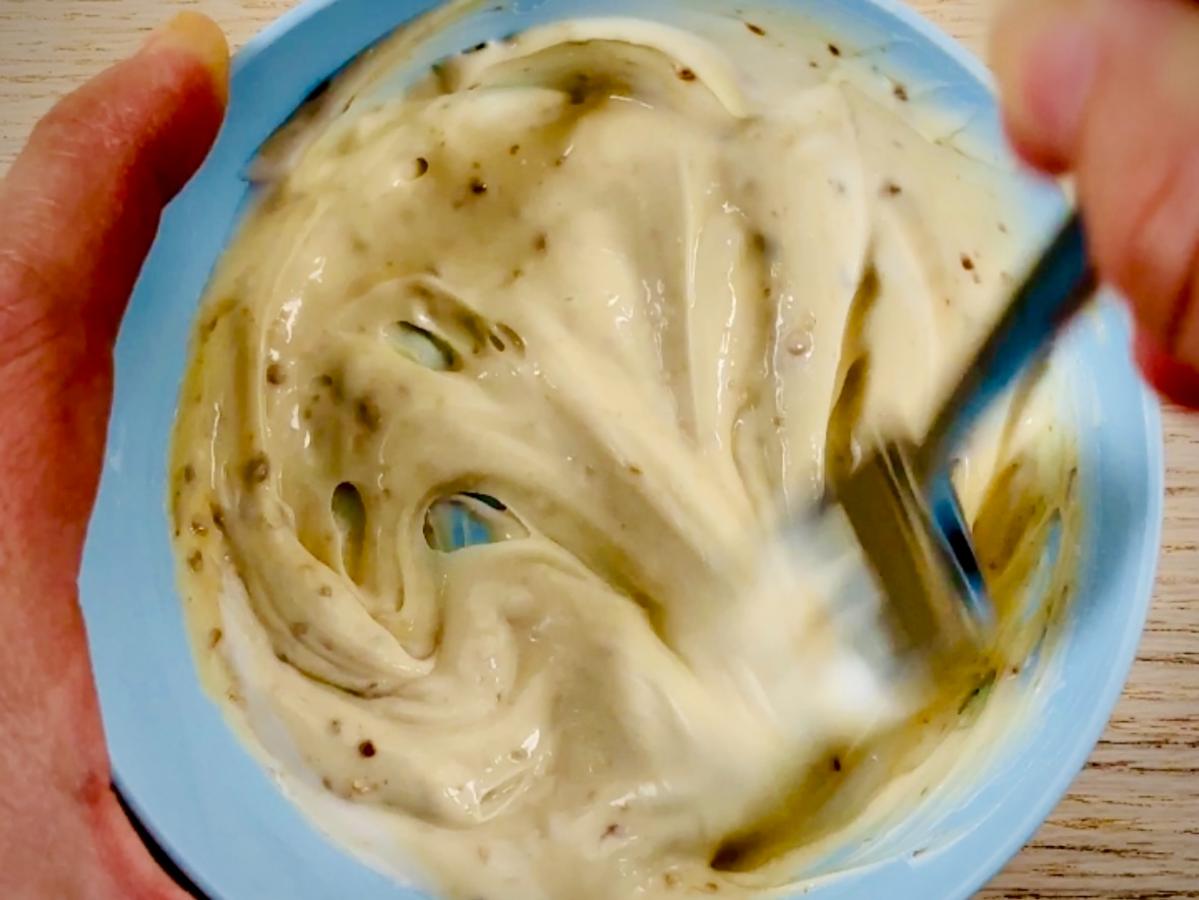 Mayonnaise and miso paste mixed together in a bowl forming a smooth light brown thick sauce.