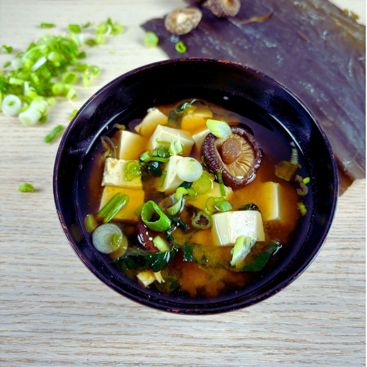 Traditional miso soup bowl filled with miso soup, tofu, shitake mushroom and spring onions.