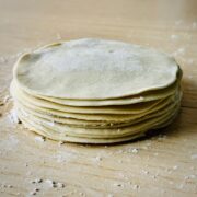 Stack of small flat rounds of gyoza wrapper dough on a flour-dusted surface