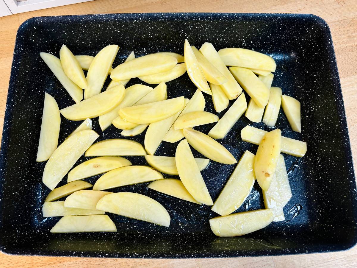 A large baking tray filled with hand-cut Maris Piper potato fries, ready for roasting in the oven.