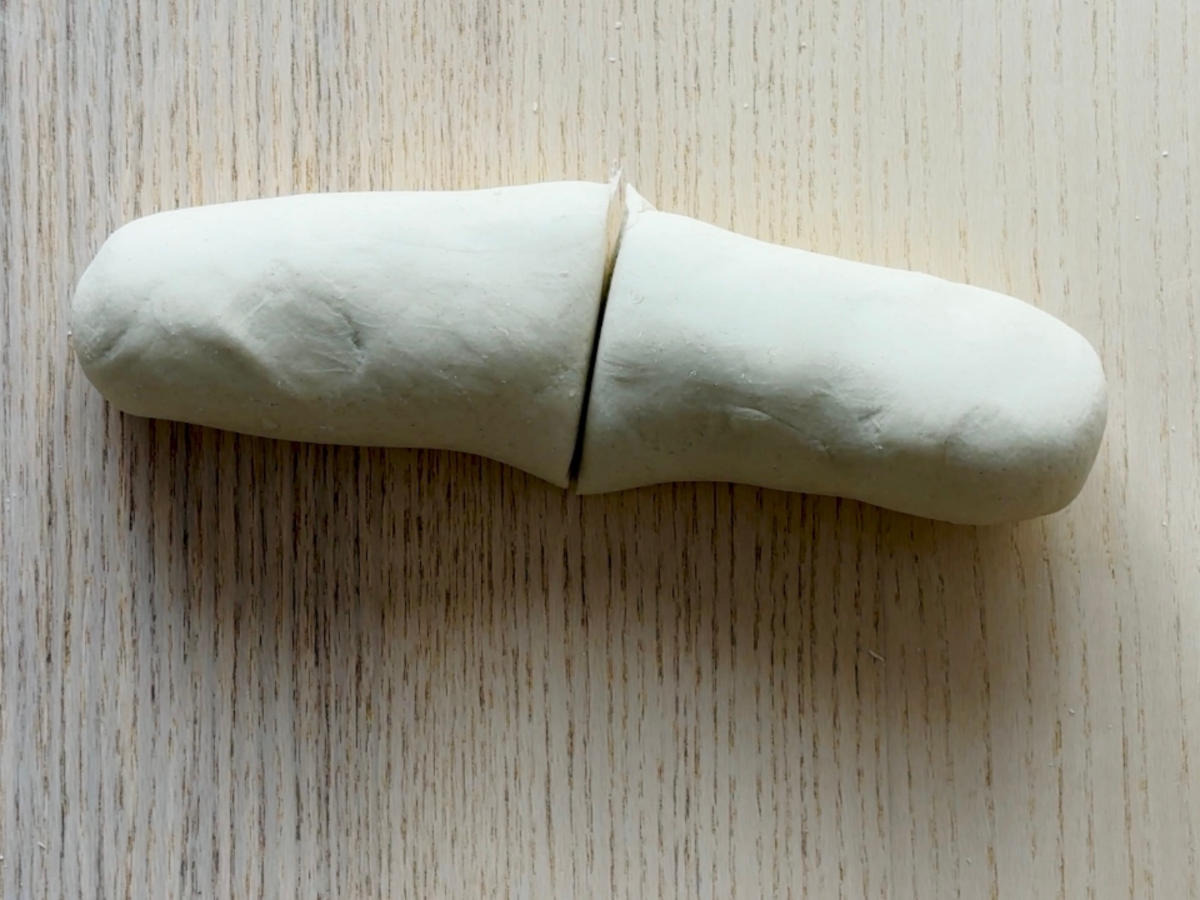 A log-shaped piece of dough cut in half.