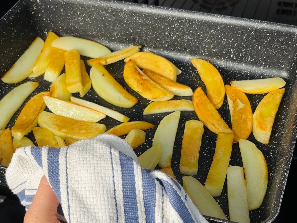 A tray of cooked potato fries coming out of the oven, having turned crisp golden brown colour, ready to be seasoned with Japanese shichimi togarashi spices.