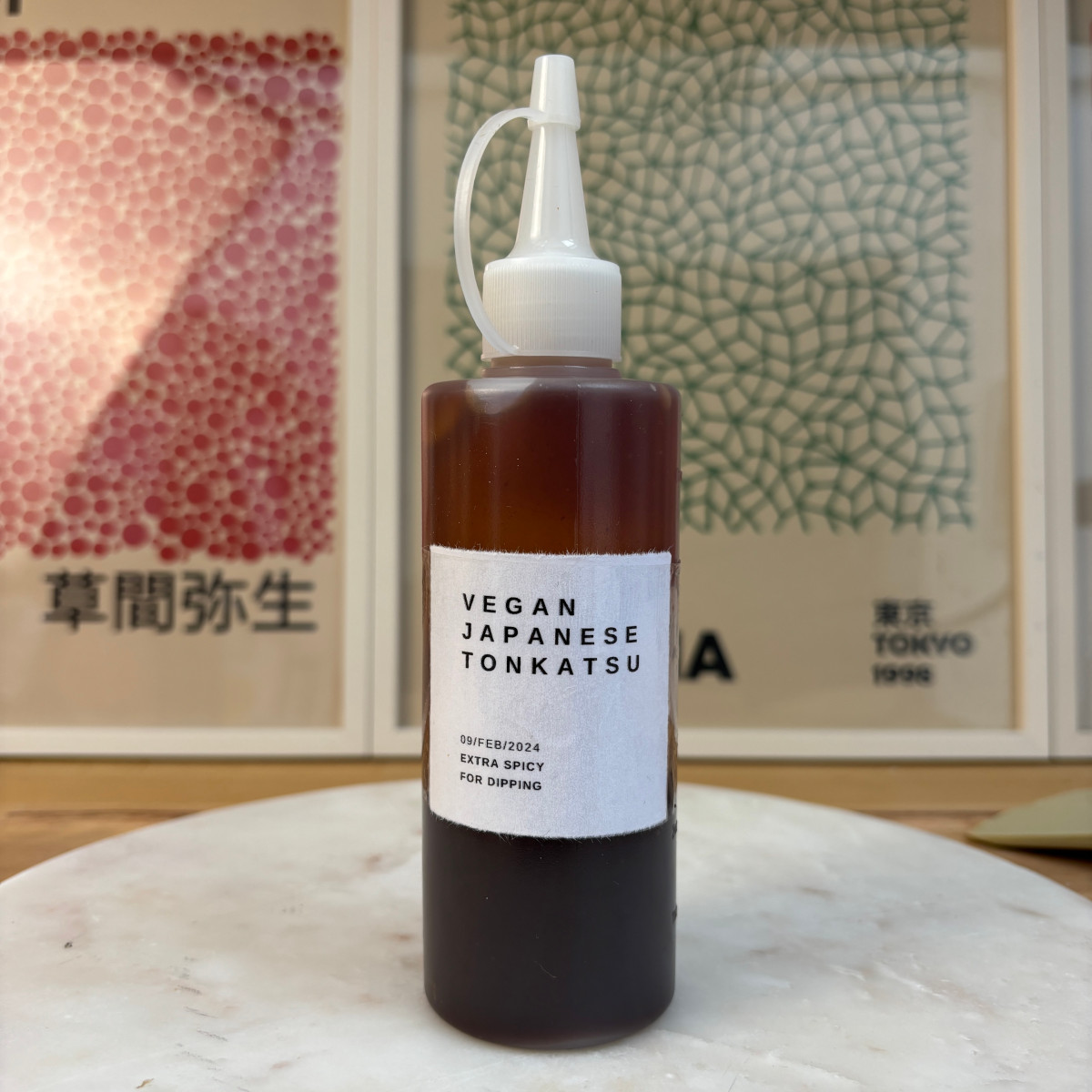 A squeezy bottle filled with brown tonkatsu sauce. This bottle is the Vegan Japanese brand, made extra spicy for dipping.