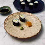 Two slices of freshly made avocado sushi maki served with wasabi and pickled ginger