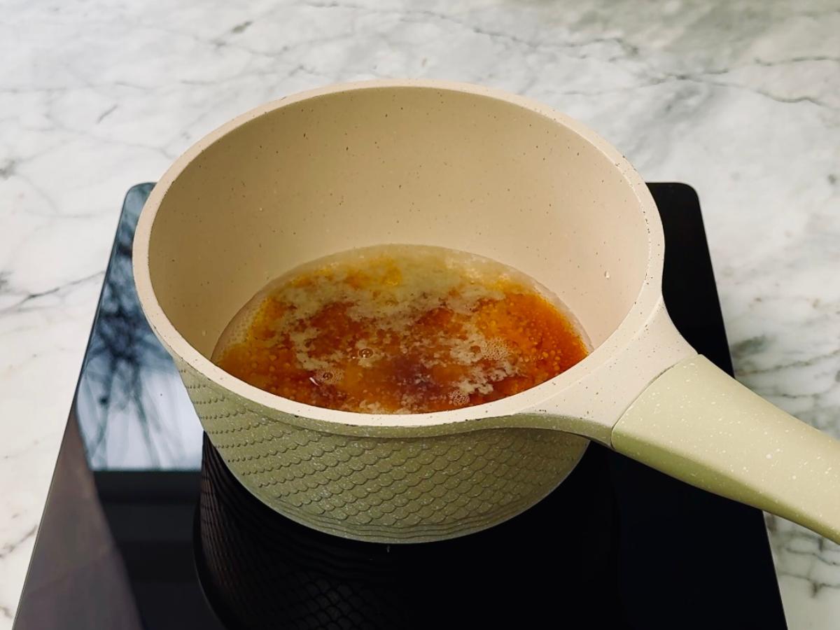 A saucepan containing dashi, soy sauce, and sugar, simmering over heat.