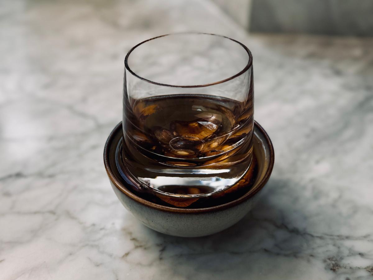 A whisky glass placed on top of the mushrooms, fully submerging them in water to soak.