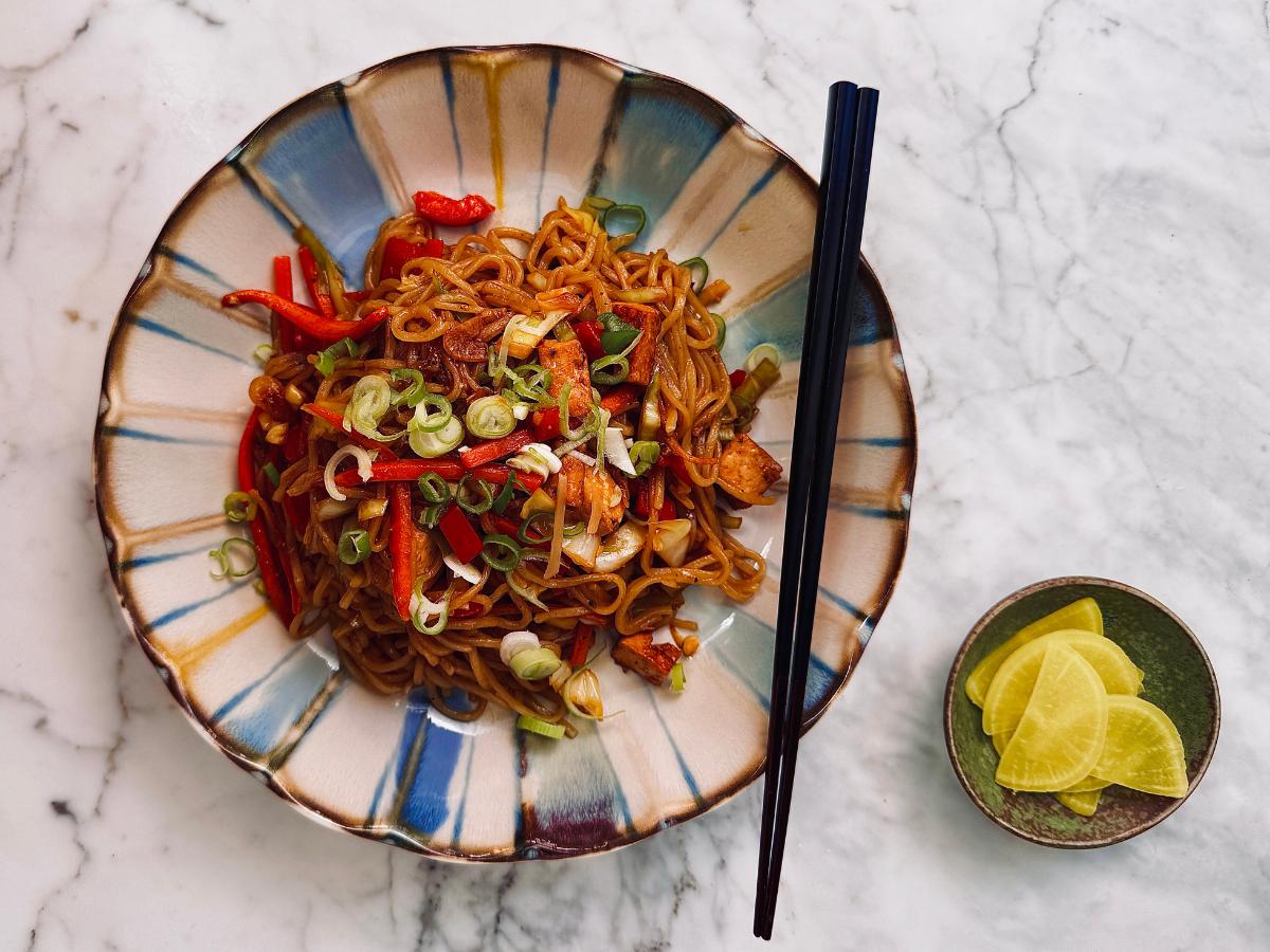 tofu noodles in a round bowl with a small side dish of takuan (pickled radish)