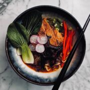 Bowl of vegan Japanese spicy ramen in rich broth topped with inari age, shiitake mushrooms and fresh vegetables