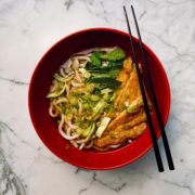 Bowl of vegan udon noodle soup with thick udon noodles in dashi broth topped with inari tofu, pak choi and spring onions