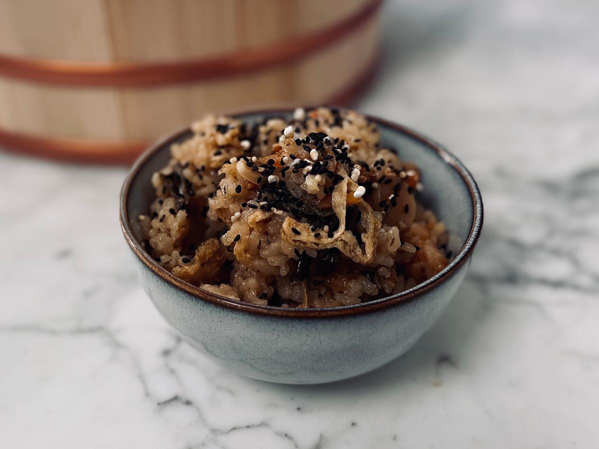 A warm bowl of sansai gohan garnished with sesame salt, ready to eat.