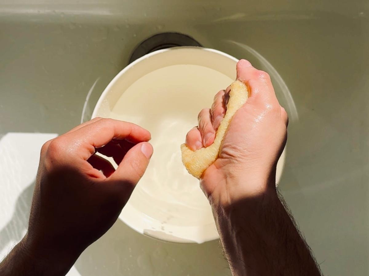 Squeezing softened abura-age over the sink after rinsing under cold water.