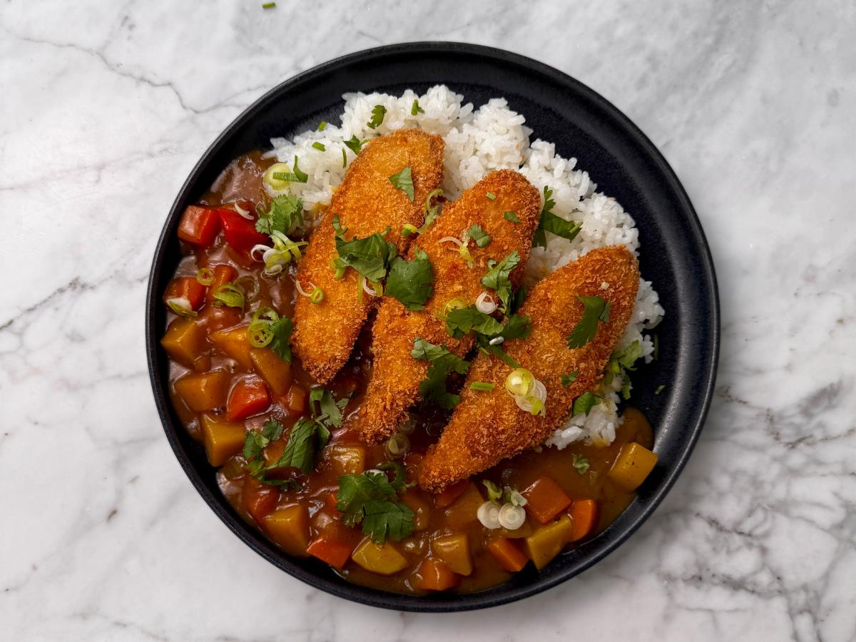 Final dish plated: a bed of rice topped with curry, sweet potato katsu, and garnished with spring onions and coriander.