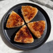 Four grilled yaki onigiri rice triangles on a round plate