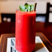 Tall glass of yuzu mango mint smoothie with a metal straw garnished with fresh mint