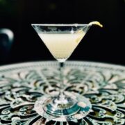 Yuzu martini cocktail garnished with lemon peel on a garden table