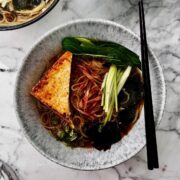 Bowl of vegan shio ramen soup noodles topped with seared tofu and greens