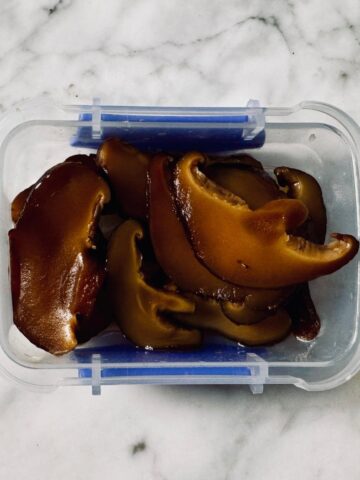 Marinated vegan Japanese sushi mushrooms in a container, ready to use in sushi.