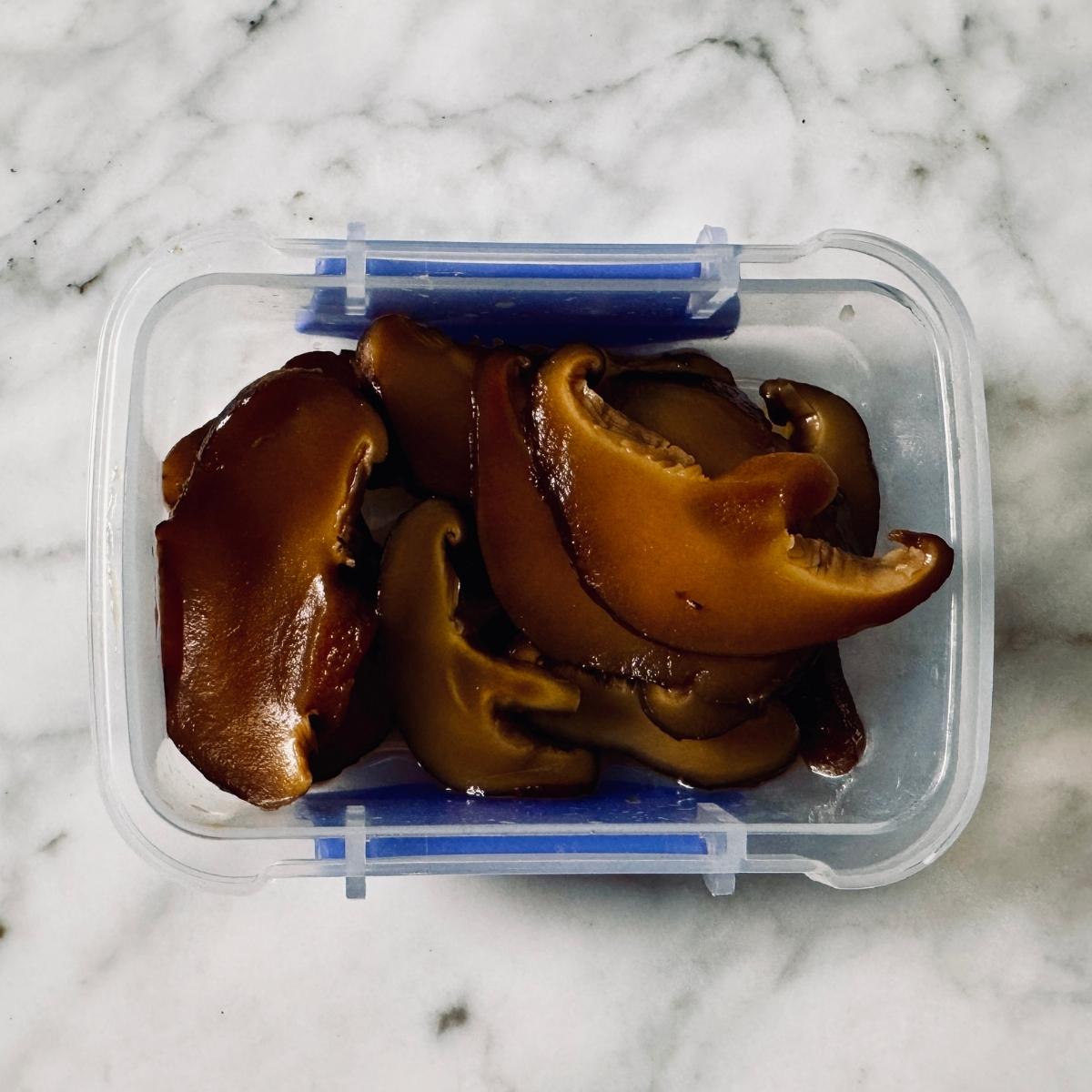 Marinated vegan Japanese sushi mushrooms in a container, ready to use in sushi.