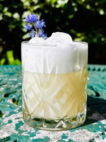 yuzu gin sour in an old fashioned glass on a garden table basking in the sunshine