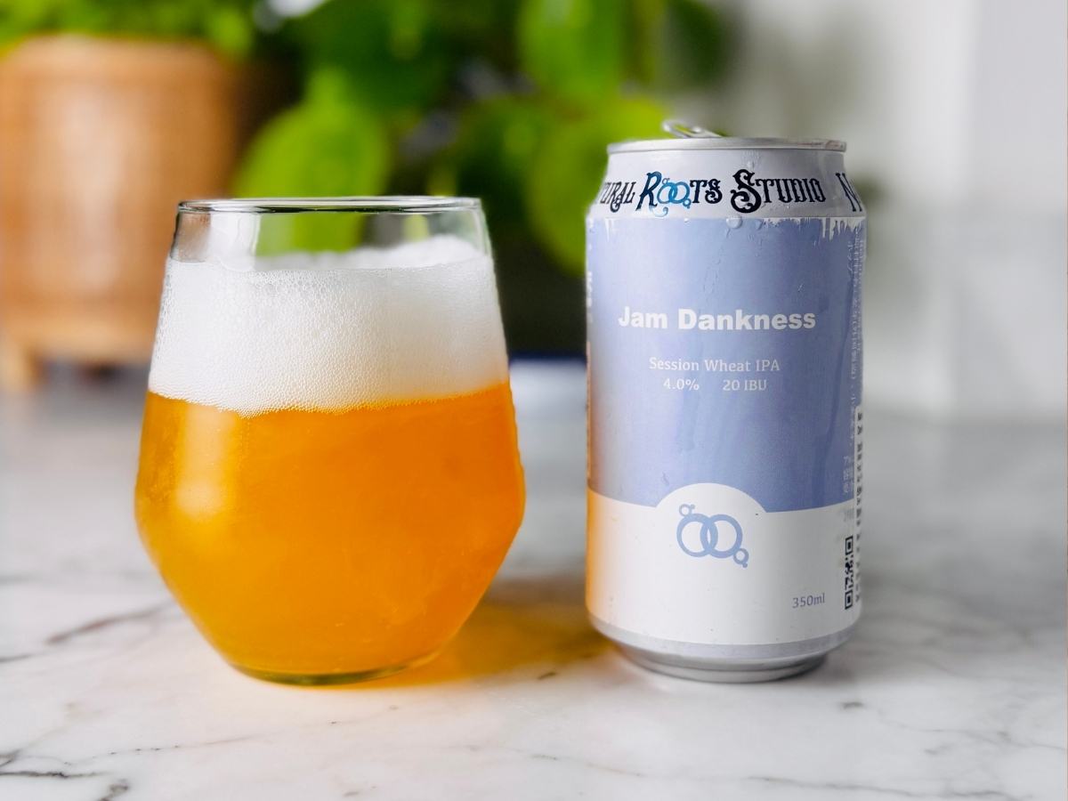 Natural Roots Jam Dankness can next to a glass of hazy golden IPA with a frothy head