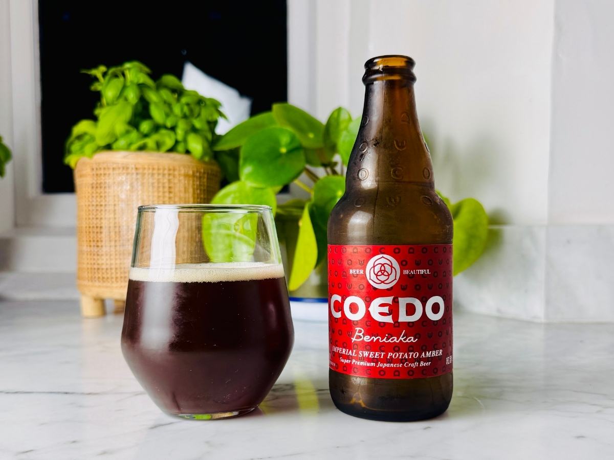Coedo Beniaka can next to a glass of reddish-amber ale with a creamy head