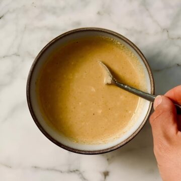 sesame dressing in bowl being stirred with a teaspoon