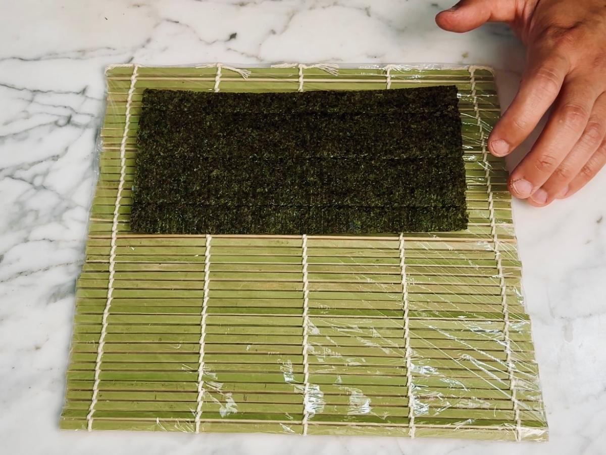 Bamboo sushi mat with a half sheet of nori placed on the bottom center.