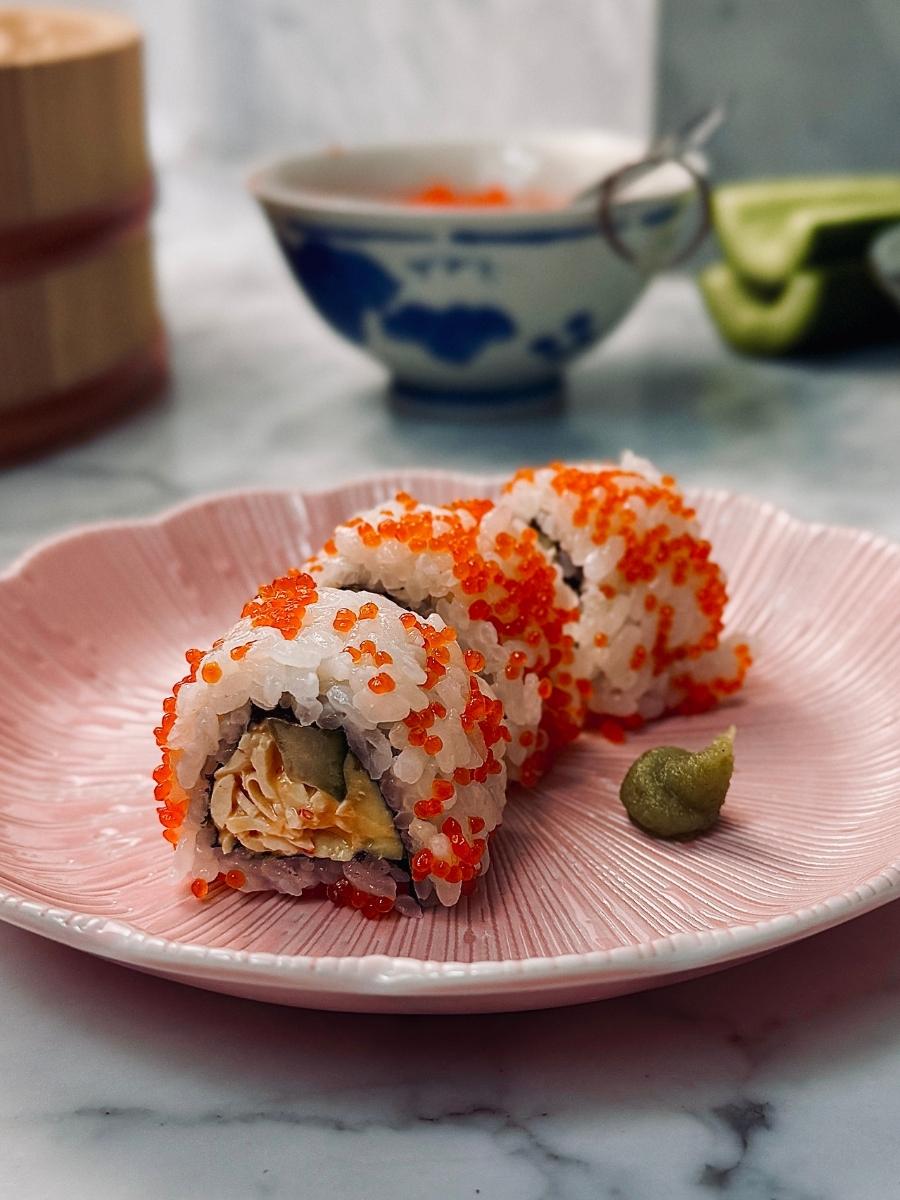 3 pieces of vegan california roll sushi on a pink plate