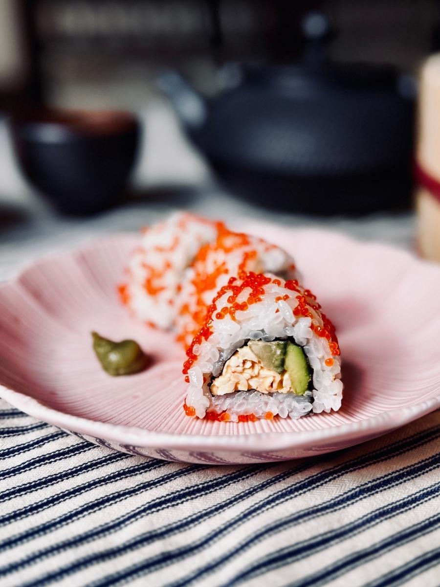 3 pieces of vegan california roll on a pink scallop edged plate
