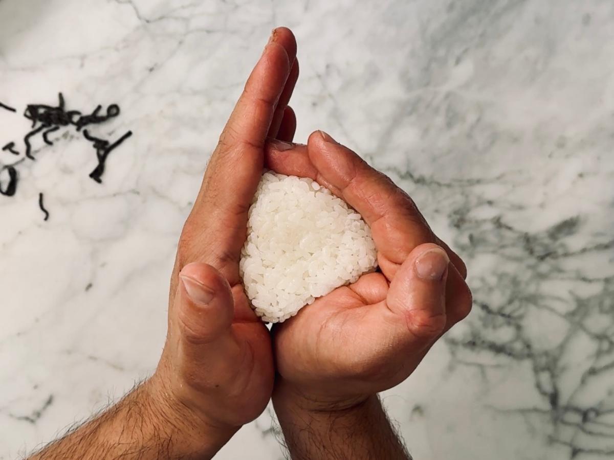 hands pressing the edges of the triangular onigiri