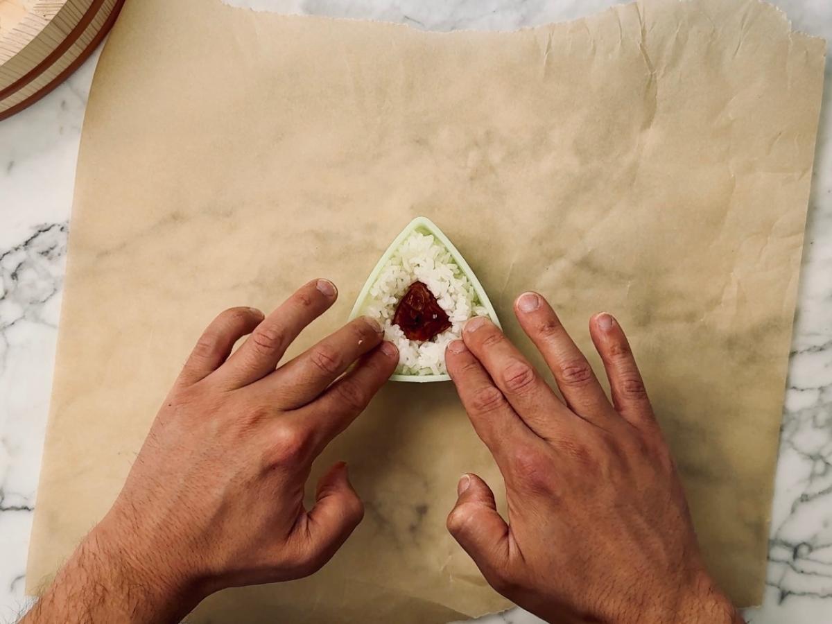 Filling an onigiri mold with rice and umeboshi.