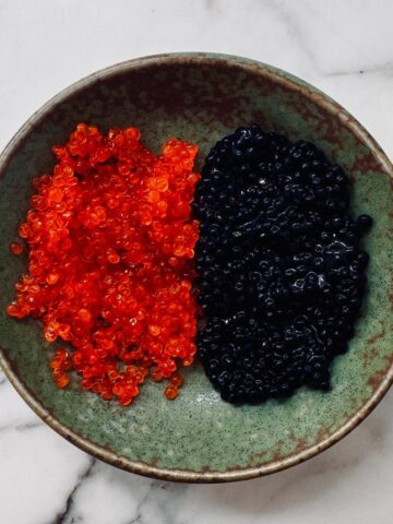 1 orange and 1 black dollop of vegan caviar on a small plate