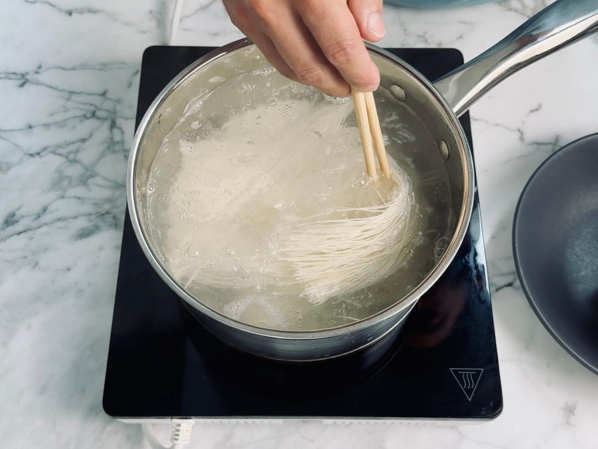 Somen noodles boiling in a large pot of water on the stove.
