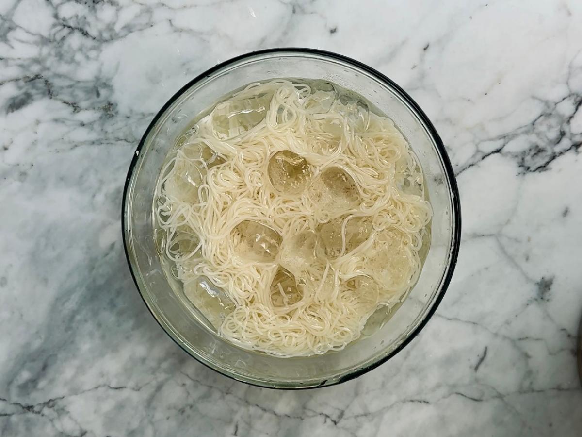 Noodles resting in a large bowl filled with ice water to chill.