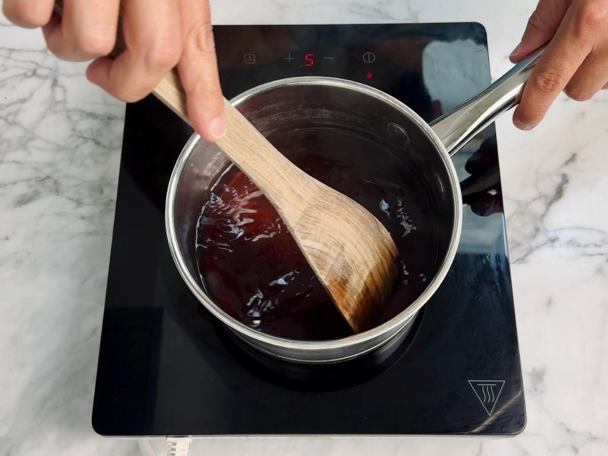 Sauce gently simmering on the stove with a wooden spatula stirring.