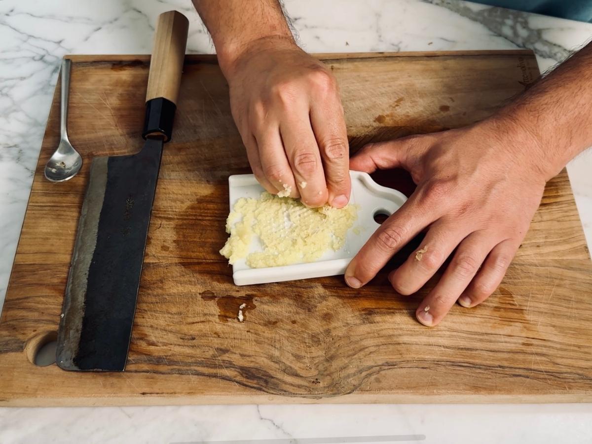 Fresh ginger being grated with a ceramic grater