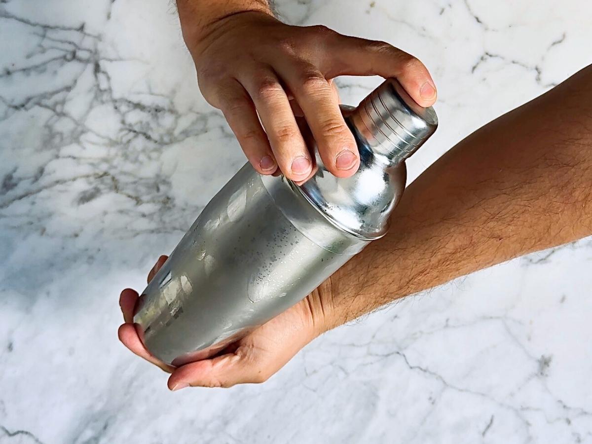 Cocktail shaker filled with ice being shaken vigorously to chill the ingredients.

