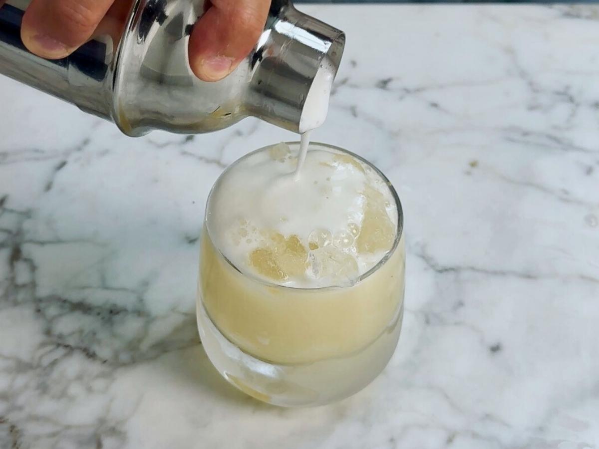 Straining the cocktail into a chilled old fashioned glass with ice.