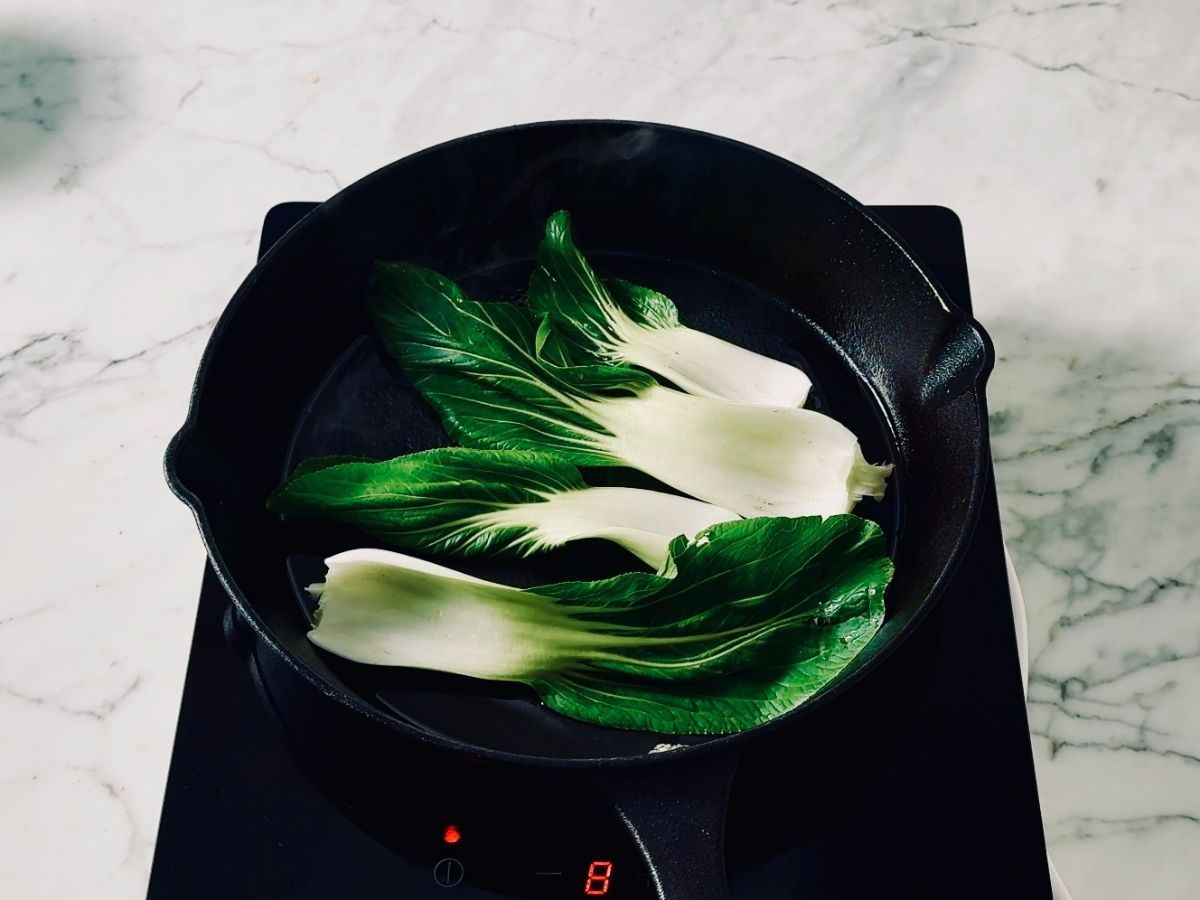 Frying bok choy in a hot sesame oil pan