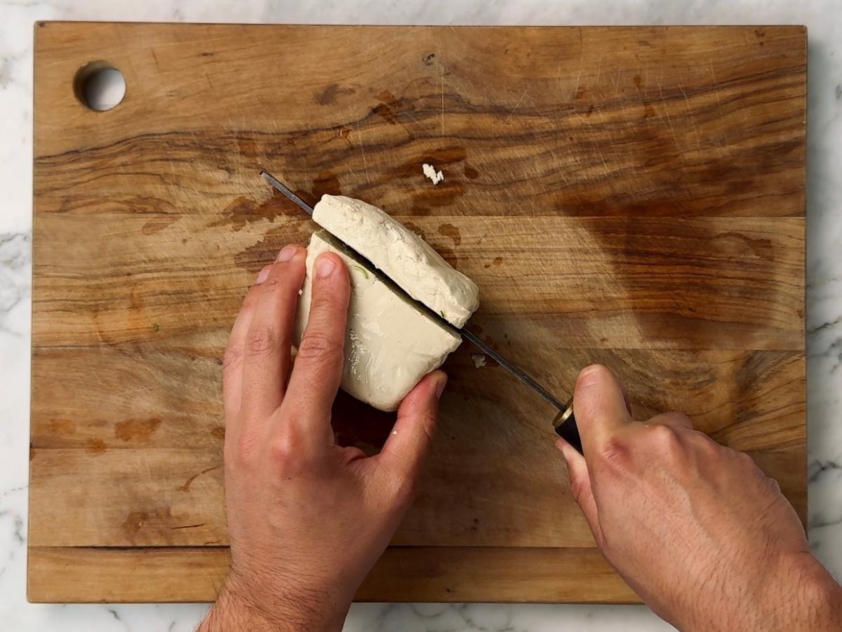 tofu being sliced into a inch thick rectangular slab