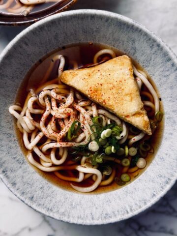 a bowl of kake udon (thick udon noodles in a translucent soy based broth)