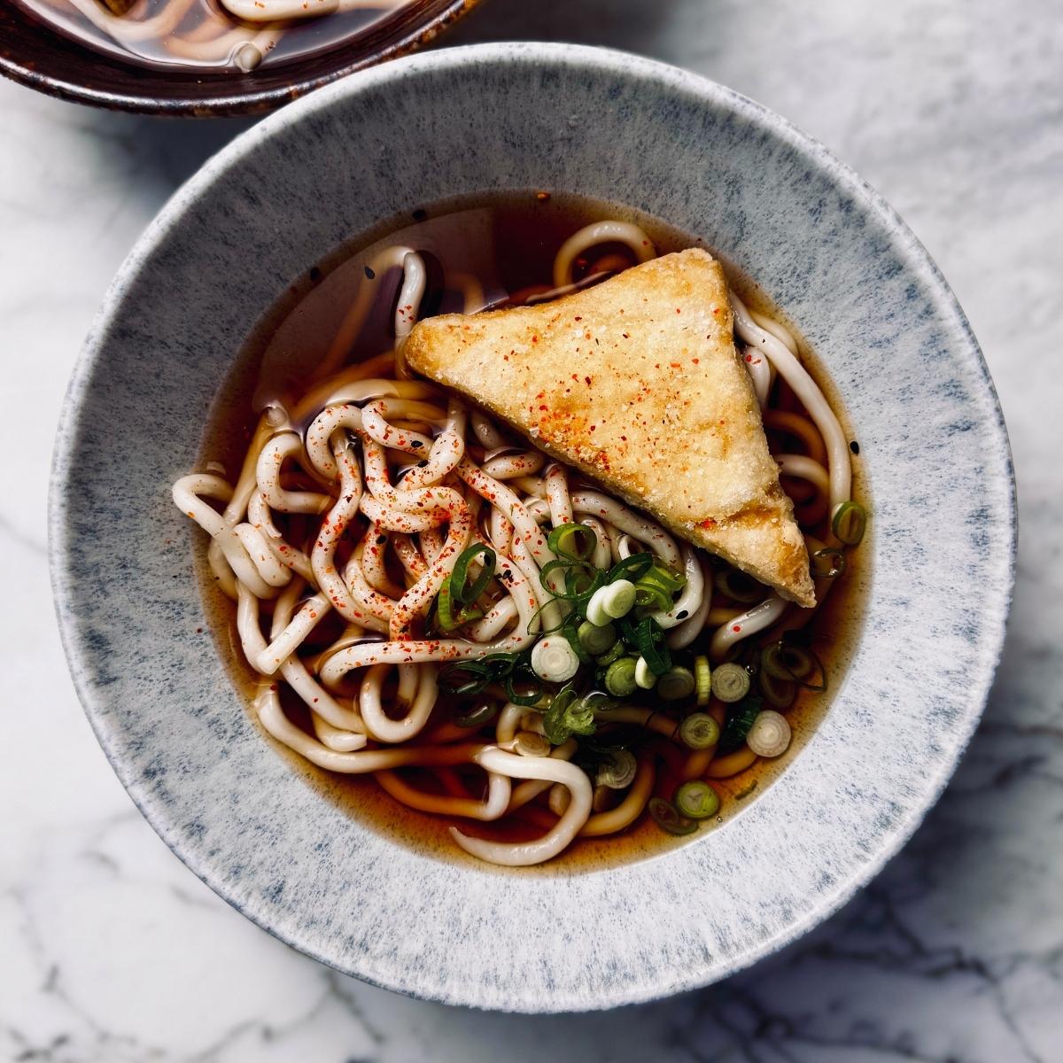 a bowl of kake udon (thick udon noodles in a translucent soy based broth)