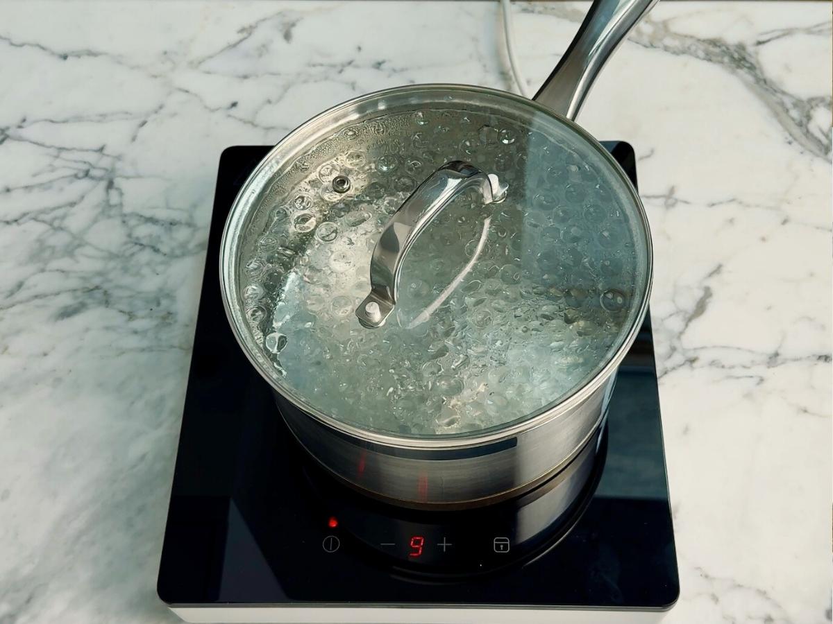 Large pot of salted water boiling on the stove, ready to cook spaghetti for miso mushroom pasta.