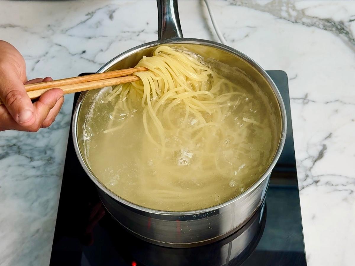Spaghetti cooking in a pot of boiling salted water for miso mushroom pasta.