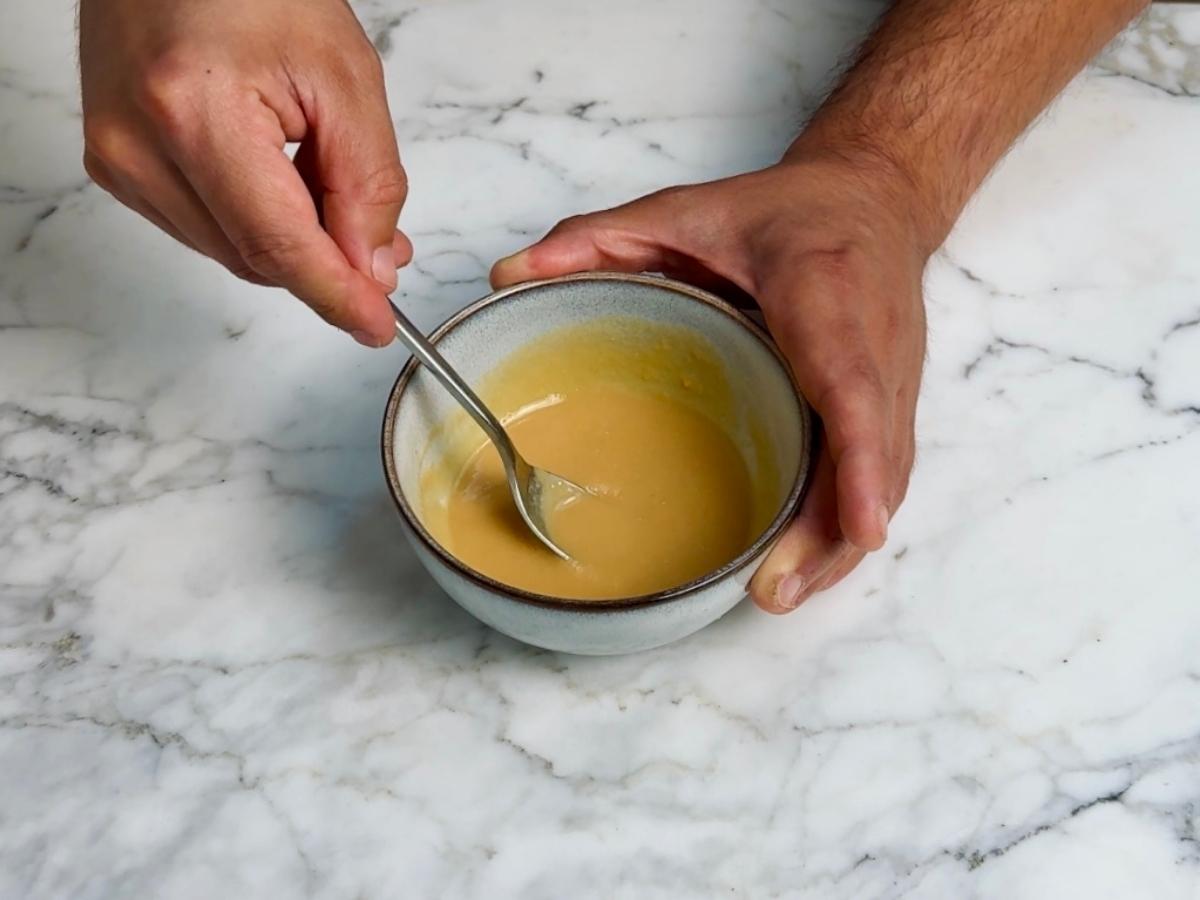 Bowl of miso paste stirred with hot water until smooth and ready for pasta sauce.