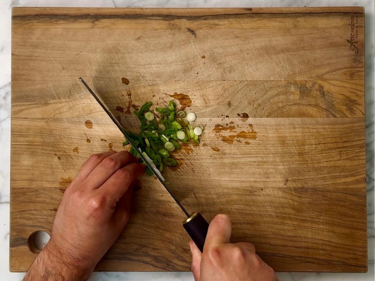 green onions being sliced into thin rounds