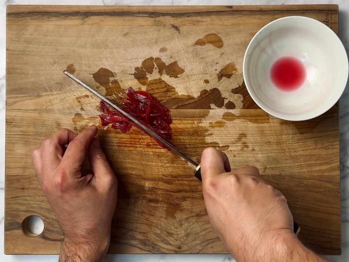 pink pickled ginger being sliced into thin shreds
