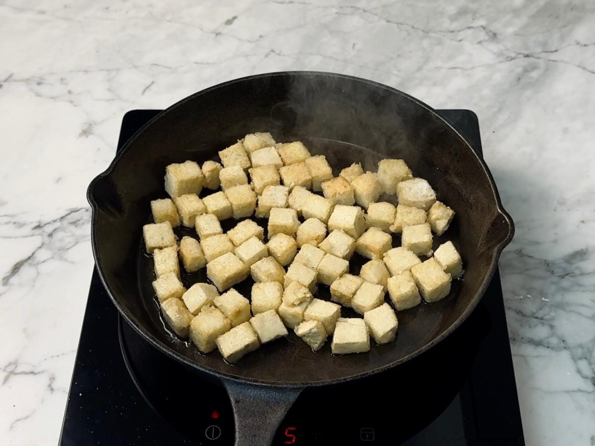 tofu cubes being fried in a skillet